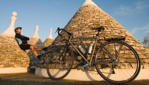 Cyclistresting against a trullo.